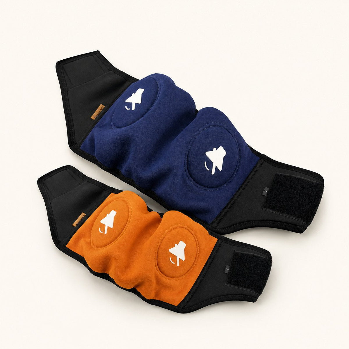 Pack Dúo SORA: dos protectores auditivos, uno azul marino y otro naranja, vistos desde arriba sobre fondo crema